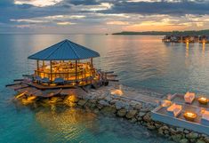 an aerial view of a restaurant on the water at sunset or dusk with lit up tables and chairs