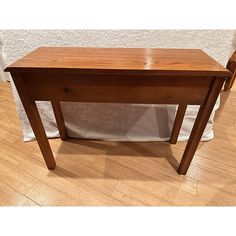 a wooden table sitting on top of a hard wood floor next to a white cloth