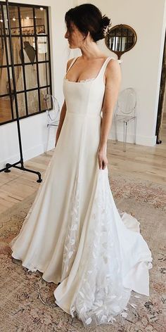 a woman in a wedding dress standing on a rug looking at her reflection in the mirror