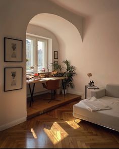 a living room with a couch, table and pictures hanging on the wall next to it