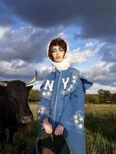 a woman in blue is standing next to a cow