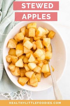 a white bowl filled with sliced apples on top of a table next to a spoon