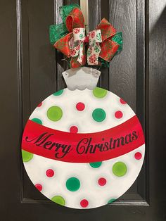 a christmas ornament hanging on a door with ribbon and bow around the top