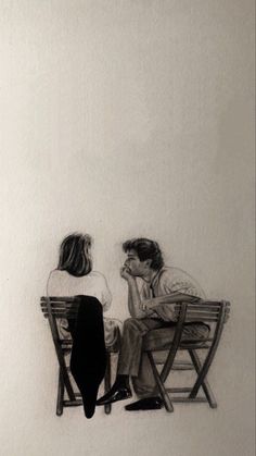 two people sitting on wooden chairs facing each other in front of a white wall and one person is holding his head down