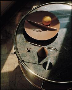 an orange sitting on top of a glass table