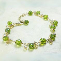 Peridot green gemstone bracelet features real peridot stones in their natural green hue, 14k gold filled wire wrapping with swirl accents at the end of each stone and more peridot gemstones as dangle accents to create a beautiful artisan bracelet.  Perfect gift for a woman who loves peridot green hues or a throughtful present for a woman born in August since peridot is her birthstone. Bracelet Details: - Natural peridot gemstones are 6 mm in diameter - Bracelet length is 8.5 inches long (21.59) Green Peridot Wire Wrapped Jewelry, Green Briolette Wire Wrapped Jewelry, Green Wire Wrapped Bracelets With Round Beads, Green Wire-wrapped Bracelets With Round Beads, Green Wire Wrapped Bracelets, Green Birthstone Bracelets For Anniversary, Elegant Green Wire Wrapped Beaded Bracelets, Green Wire Wrapped Jewelry For May Birthstone, Green Birthstone Bracelet For Anniversary