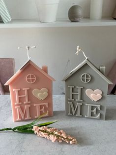 two small houses are sitting on the table next to each other, one has a flower in front of it