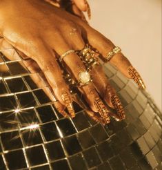 a woman's hand with hennap and rings on top of a mirror