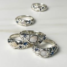 These opulent rings are bursting with the ocean's bounty, bringing together beach stones, sapphires, and barnacles in unique and playful combinations. Each piece is one-of-a-kind, handmade and released in small batches. DetailsSolid sterling silver3 sapphires per ring1-2 Nantucket beach stones per ring The Nereids were goddesses of the sea's rich bounty and protectors of sailors and fishermen. They were the daughters of Nereus and lived in a silvery grotto at the bottom of the Aegean Sea. Beach Engagement Rings, Beach Jewelry Rings, Ocean Inspired Wedding Rings, Sea Inspired Rings, Ring Inspo Jewelry Silver, Barnacle Jewelry, Mermaid Rings, Silver Shell-shaped Ocean-inspired Jewelry, Handmade Silver Rings With Ocean-inspired Style