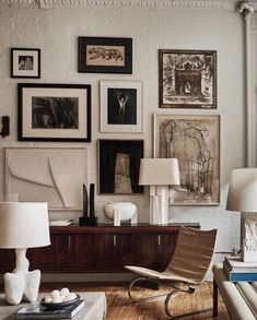 a living room filled with furniture and pictures on the wall next to a table lamp