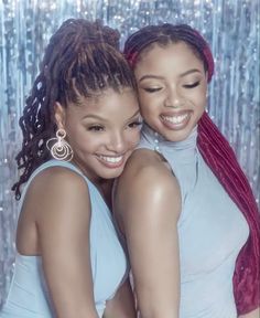 two young women hugging each other in front of a wall with sequins on it