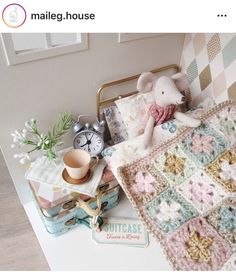 there is a crocheted blanket on the table next to an alarm clock and other items