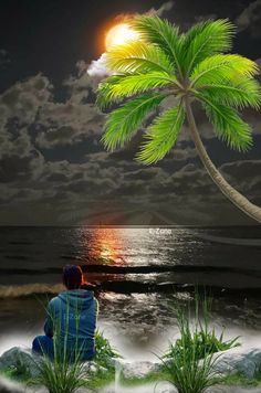 a man sitting on the beach under a palm tree at night with the moon in the sky