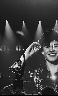 a black and white photo of a man on stage with his hands in the air