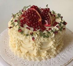 a cake with white frosting and pomegranates on top is sitting on a plate