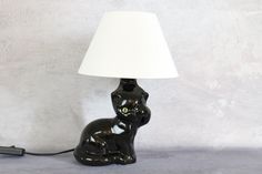 a black cat lamp sitting on top of a table next to a white lampshade