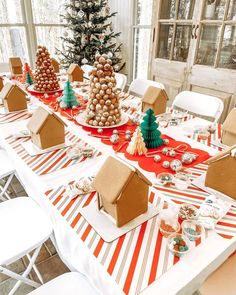 the table is set up with gingerbread houses and candy trees on top of them