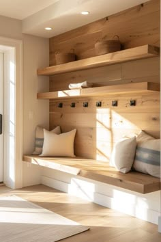 a room with wooden shelves and pillows on top of the shelf, in front of a white door