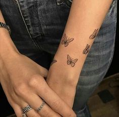 a woman's arm with butterfly tattoos on her left wrist and the other hand