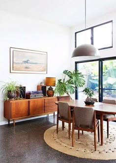 a dining room table and chairs with plants on the rugs in front of it