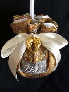 a christmas ornament hanging from a white and gold ribbon on a black background