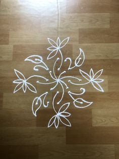 a wooden floor with a flower design drawn on the ground in white chalk and colored pencils