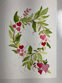 a watercolor painting of a heart wreath with leaves and berries on white paper background