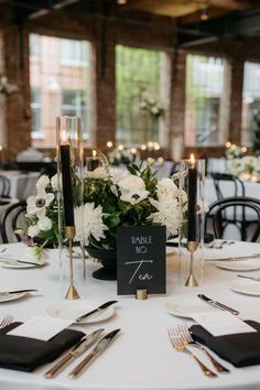 the table is set with black and white place cards, silverware, and flowers