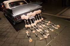 an old car parked on the street with flowers attached to it