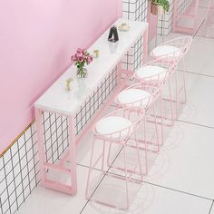 four pink chairs and a white table with flowers on it in a room that is painted pink