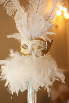 a white mask with feathers in a vase