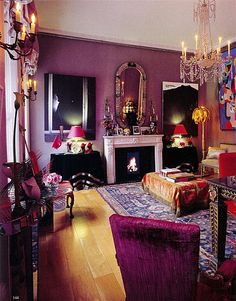 a living room filled with furniture and a fire place under a chandelier in front of a fireplace