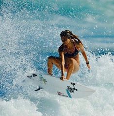 a woman riding a wave on top of a white surfboard in the middle of the ocean