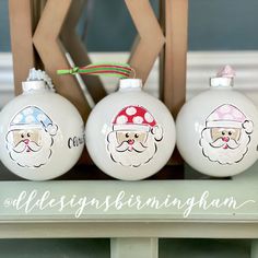 three glass christmas ornaments with santa's faces on them