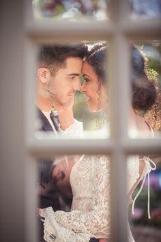 the bride and groom are looking at each other through an open window in their wedding day