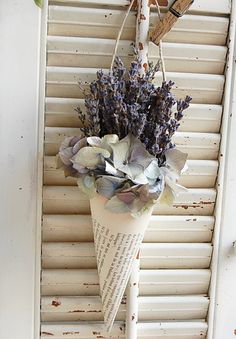 a vase filled with flowers sitting on top of a window sill next to shutters