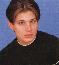 an old photo of a young man in a black shirt with a cross on his neck