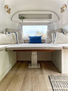 there is a bench with pillows on it in the living room or dining area at this camper