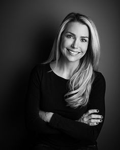 a black and white photo of a woman with long blonde hair smiling at the camera