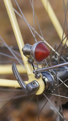 the front wheel of a bicycle with spokes and red light on it's brake