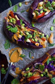 baked sweet potatoes with colorful vegetables and sauce on parchment paper, ready to be eaten