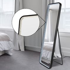 a large mirror sitting on top of a floor next to a bed