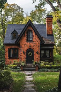 a brick house with black shingles and windows in the front yard, surrounded by trees