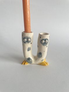 a ceramic pipe holder with an owl design on the side and a wooden stick sticking out of it