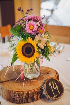 a vase filled with flowers sitting on top of a wooden slice next to a table