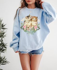 This is the Vintage Kitten Crewneck Sweatshirt. The soft, warm material is made from a blend of cotton and polyester. It has no itchy side seems and a trendy, loose fit. The cool design on this cottagecore crewneck features a collage of vintage kitty and flower illustrations salvaged from old books and ephemera. PLEASE SIZE UP 2-3 SIZES FOR A TRENDY, LOOSE FIT! This design is created by Jillian Anderson @ A Living Whimsy. She uses digital graphic design elements and collage and optimizes each im Jillian Anderson, Coquette Cat, Sweater Aesthetic, Aesthetic Crewneck, Cottagecore Sweater, Cat Sweater, Graphic Design Elements, Floral Sweater, Cat Sweatshirt