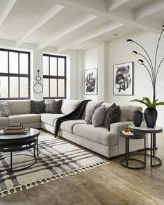 a living room filled with lots of furniture next to large windows and a rug on the floor