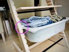 a white tub filled with clothes on top of a wooden floor