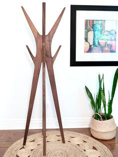 a wooden sculpture sitting on top of a rug next to a potted plant