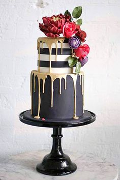 a black and gold cake with flowers on top